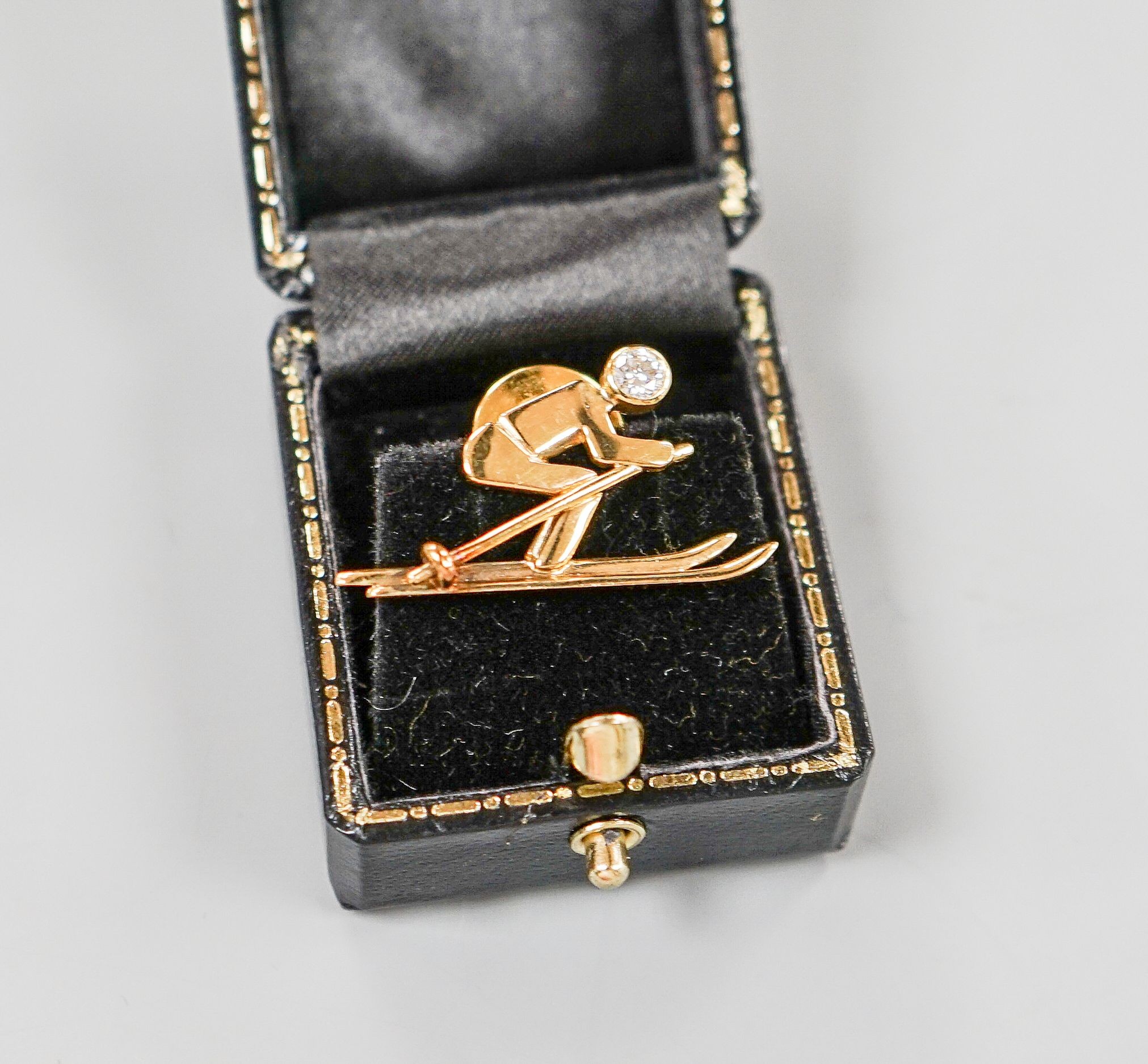 A yellow metal and single stone diamond set dress stud?, modelled as a skier, 31mm, gross 4.5 grams.